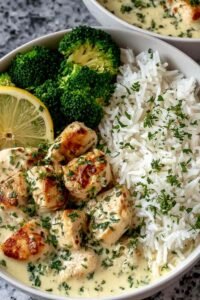 Creamy garlic chicken rice bowl with golden chicken bites in Parmesan cream sauce over fluffy white rice with steamed broccoli and fresh parsley
