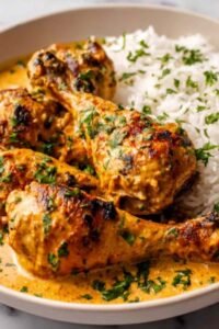 Creamy paprika chicken drumsticks in a cast iron skillet smothered in smoky paprika cream sauce with fresh parsley garnish