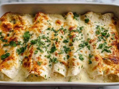 White Chicken Enchiladas with creamy white sauce and bubbling melted cheese in a 9x13 baking dish
