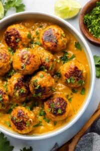 Curry chicken meatballs coated in creamy coconut curry sauce served in a skillet