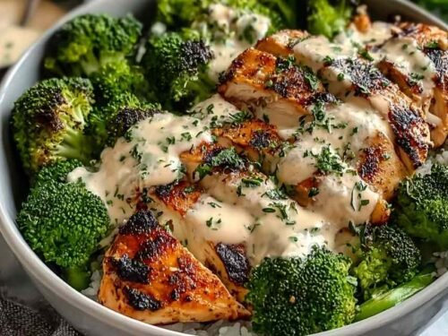 Grilled chicken broccoli bowls with creamy garlic Parmesan sauce served in a white bowl