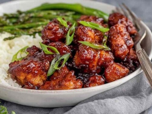 Honey butter chicken glazed in sticky caramel sauce served over white rice and garnished with sliced green onions
