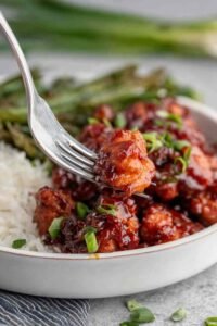 Honey butter chicken glazed in sticky caramel sauce served over white rice and garnished with sliced green onions