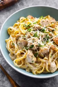 Creamy Instant Pot Chicken Alfredo served in a white bowl with fresh parsley garnish