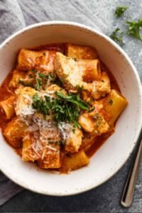 Instant Pot chicken parmesan pasta in an Instant Pot with melted mozzarella and Parmesan cheese and fresh basil garnish