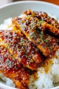 Lazy Honey Garlic Chicken pieces coated in sticky honey garlic sauce served over steamed jasmine rice, garnished with sesame seeds and green onions