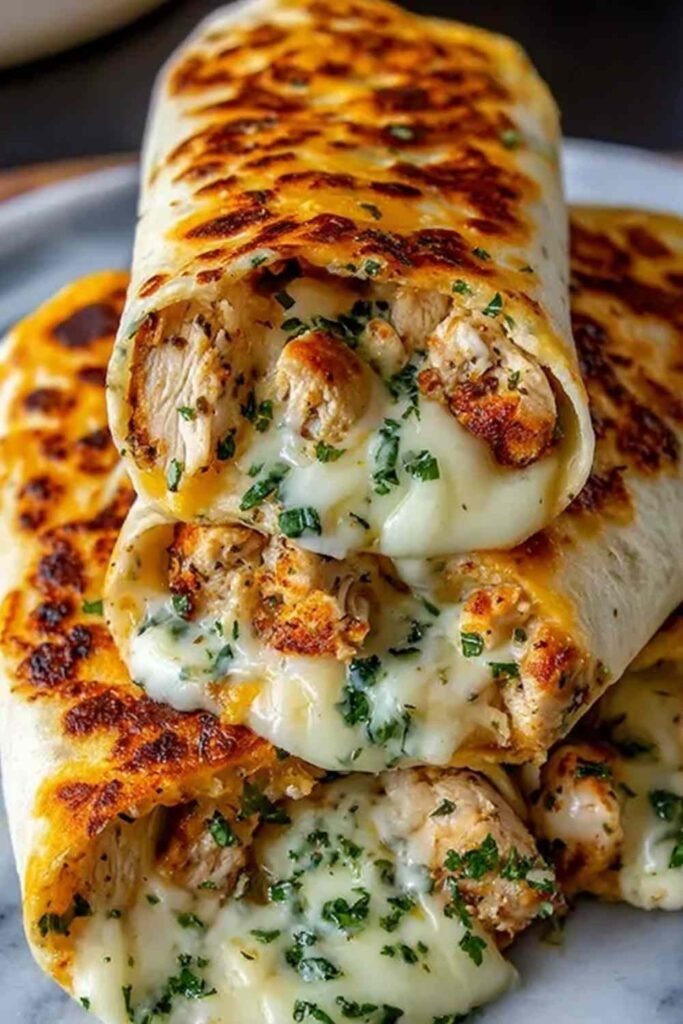 Golden low carb cheesy garlic chicken wraps sliced in half on a white plate, garnished with fresh parsley