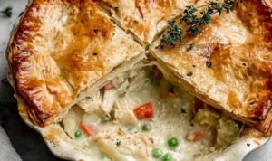 Old-Fashioned Chicken Pot Pie Homemade Old-Fashioned Chicken Pot Pie being assembled in a glass pie dish with creamy chicken vegetable filling and second pie crust being placed on top
