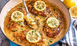 One-pan Chicken Francese with golden egg-coated chicken simmering in a lemon butter sauce in a cast-iron skillet
