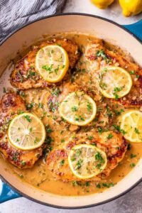 One-pan Chicken Francese with golden egg-coated chicken simmering in a lemon butter sauce in a cast-iron skillet