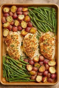 Parmesan Crusted Chicken Sheet Pan Dinner with golden chicken breasts, roasted red potatoes, and green beans on a sheet pan