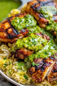 Peruvian chicken and rice with green sauce served on a plate with lime wedges and fresh cilantro
