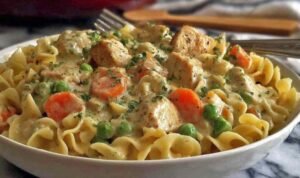 Chicken Pot Pie Pasta Chicken pot pie pasta in a white bowl with creamy sauce, tender chicken chunks, and mixed vegetables over egg noodles