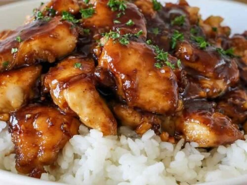 Sticky Honey Butter Chicken in a skillet coated in a rich honey garlic glaze garnished with fresh parsley
