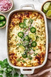 Salsa Verde Chicken Casserole with golden melted cheese and fresh cilantro garnish in a white baking dish