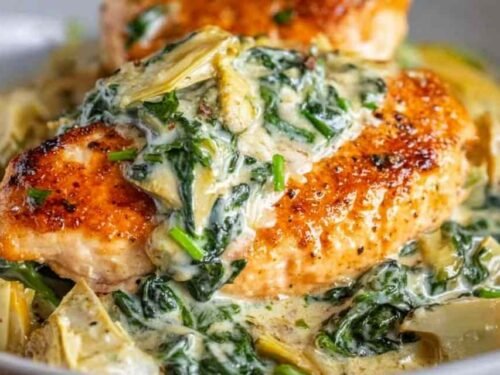 Creamy spinach artichoke chicken in a skillet with Parmesan cheese and wilted spinach